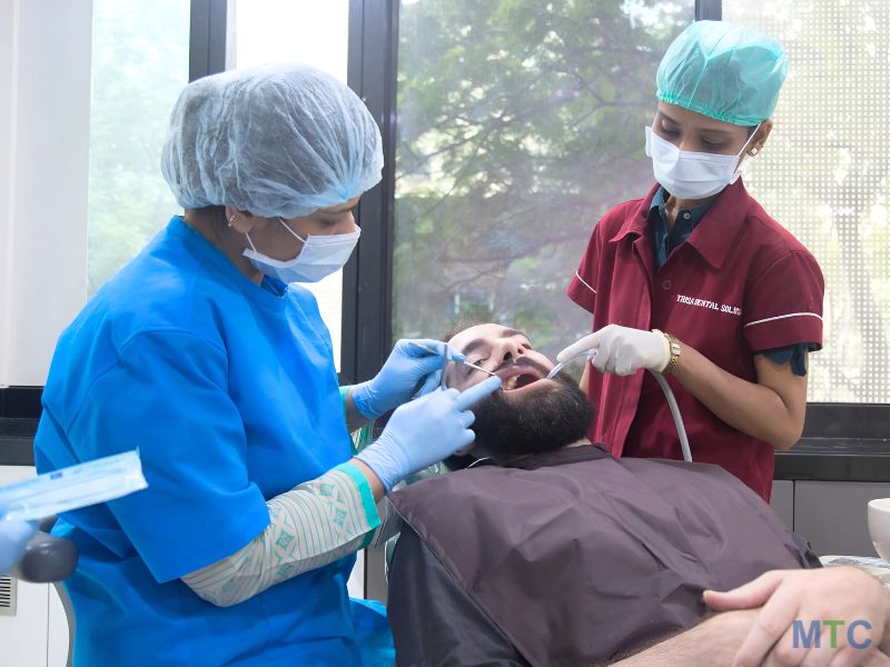 Dentist performing dental procedure at Trisa Dental