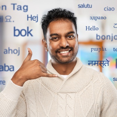 Indian man in sweater making call gesture while hello from different languages around him