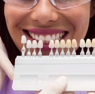 A female patient smiling as she matches her tooth shade for veneers.