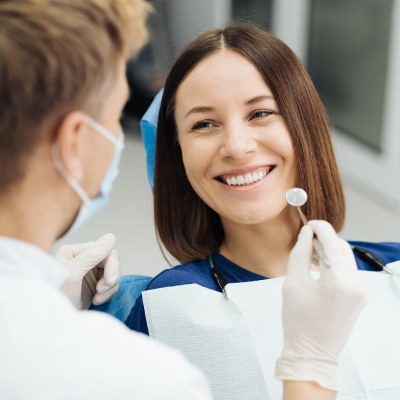 a happy patient on a dental chair smiling at her dentist