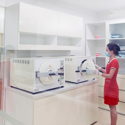 A female dental assistant placing instruments for sterilization in an autoclave