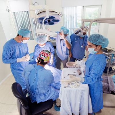 A team of 6 dental professionals treating a patient