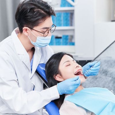 A dentist diagnosing a female patient on the dental chair