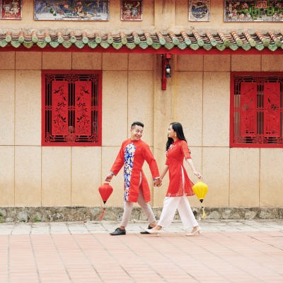 a happy couple on the streets of Vietnam in traditional red Vietnamese attire