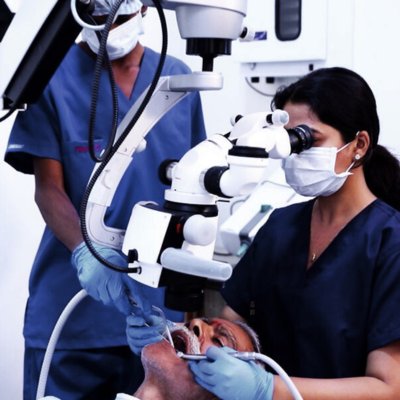 a female indian dentist doing dental treatment of an old Indian man