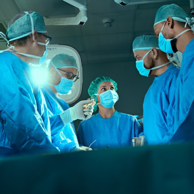 a group of 5 doctors inside an operation theatre with masks, gloves and scrub suit