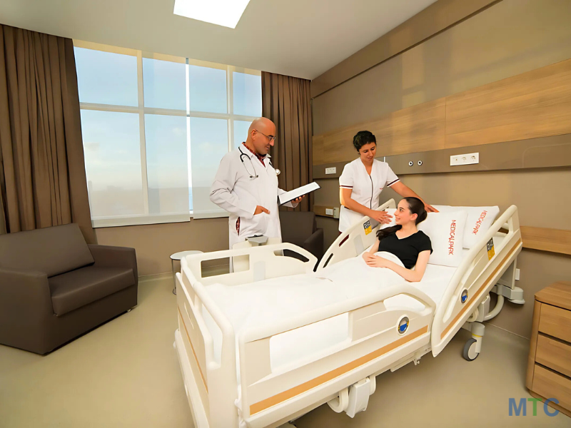 Modern private hospital ward with a female patient resting in bed while two doctors discuss her treatment in a professional and caring environment