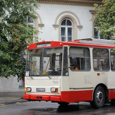 front shot of a red and white colored bus with a white building in the background