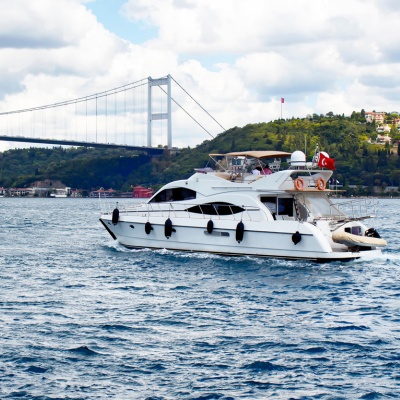 A small white cruise ship sailing through the Bosphorus Strait, surrounded by scenic waters and city views