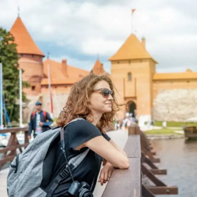 Woman standing on a bridge in Lithuania, gazing over the water, smiling