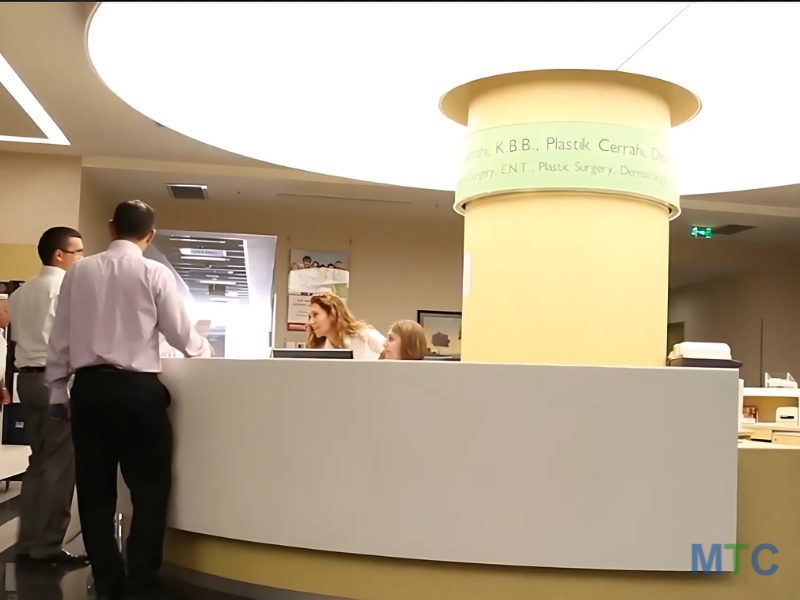 Round reception desk with yellow pillars, where people are consulting with the receptionist in a welcoming setting.