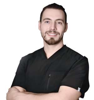 Dr. Alonso Casafont in a black scrub top, with short hair and a beard, smiling confidently with arms crossed.