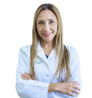 Dr. Silvia Odio in a white lab coat with long blonde hair, smiling confidently with arms crossed